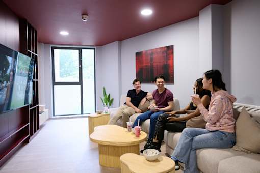 A group of people are sitting on a couch in a room with a red ceiling.