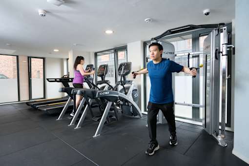 A man and a woman are working out in a gym.