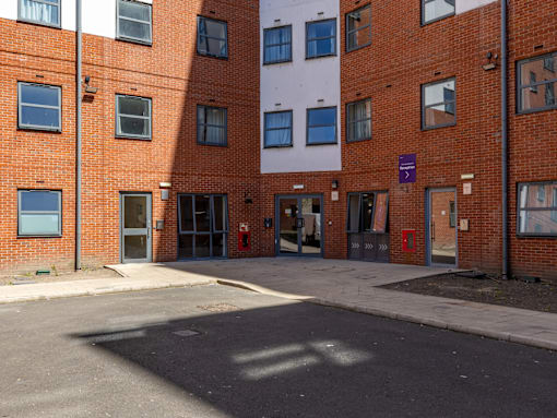 A red brick building with a white building in the background.