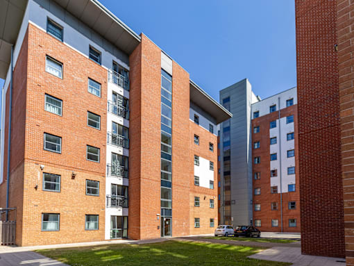 A red brick building with a white car parked in front.