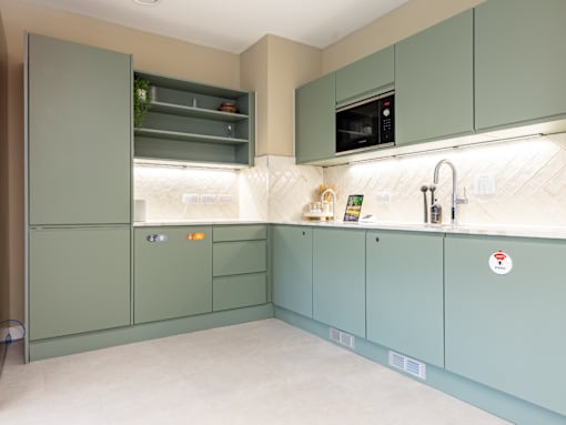 A kitchen with green cabinets and a white countertop.