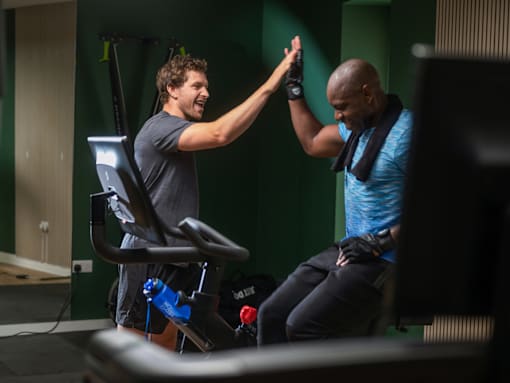 A man in a black shirt is giving a high five to another man in a blue shirt.