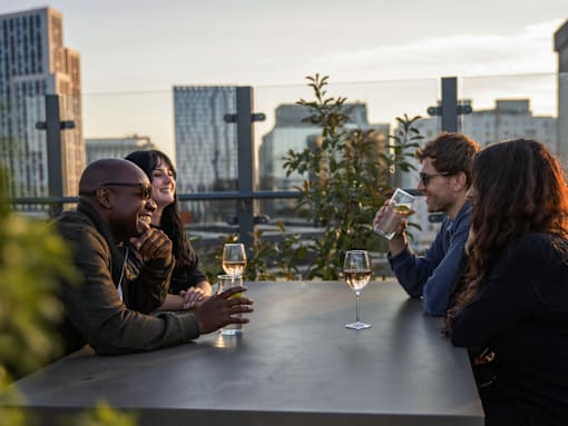 Four people sitting at a table with wine glasses.