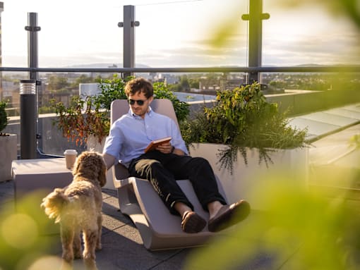 A man is sitting on a bench with a dog beside him.