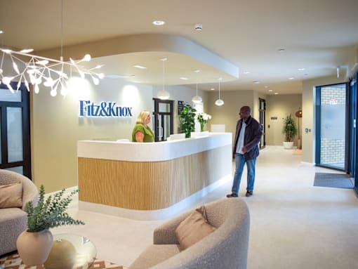 A reception area with a receptionist and a man walking in.