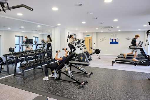 A gym with people working out and a mirror on the wall.
