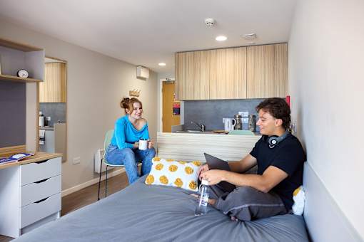 A man and a woman are sitting on a bed in a room.