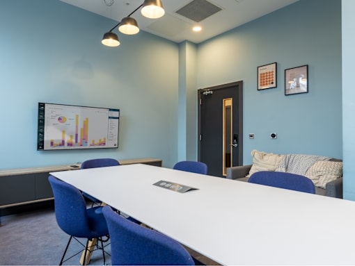 A conference room with a white table and blue chairs.