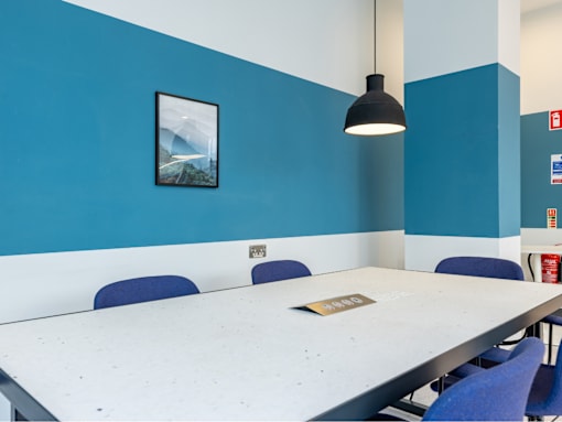 A conference room with a long table and blue chairs.