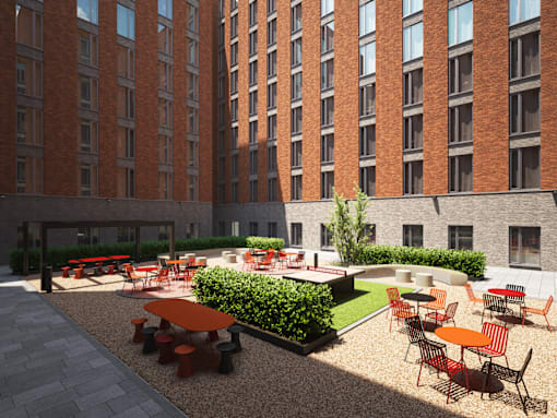 A courtyard with tables and chairs surrounded by red brick buildings.