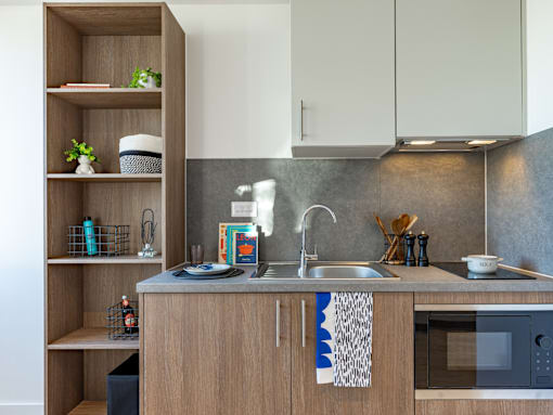 A modern kitchen with a wooden counter and a grey backsplash.