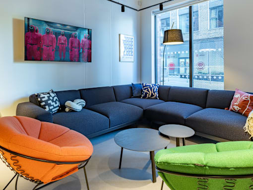 A living room with a grey couch, orange chair, and green chair.