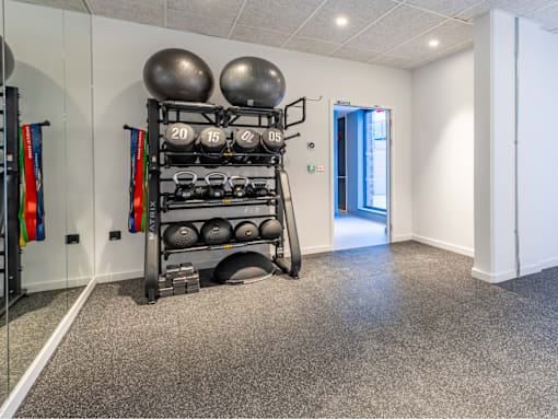 A gym room with a rack of weights and exercise balls.