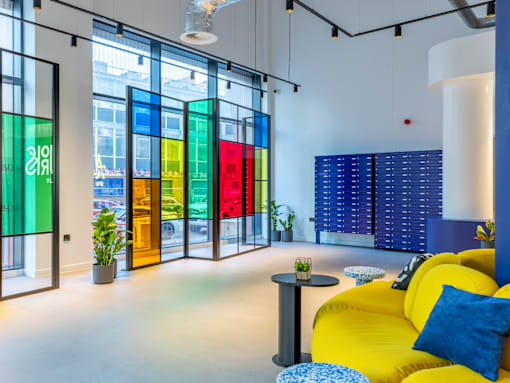 A brightly colored interior with a yellow sofa and a table with a blue and white cushion.