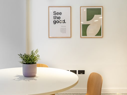A white table with a plant on it and two framed pictures on the wall.