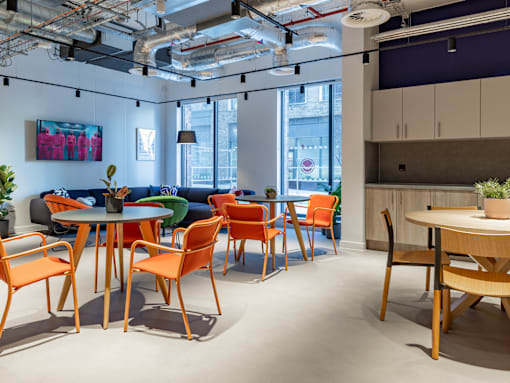 A modern office space with orange chairs and a wooden table.