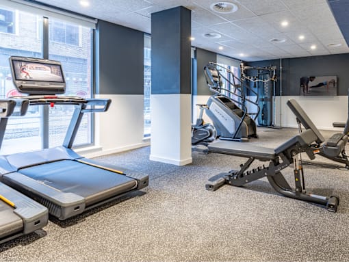 A gym with treadmills, weights, and a television.