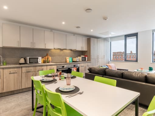 a kitchen and living room with a white table and green chairs