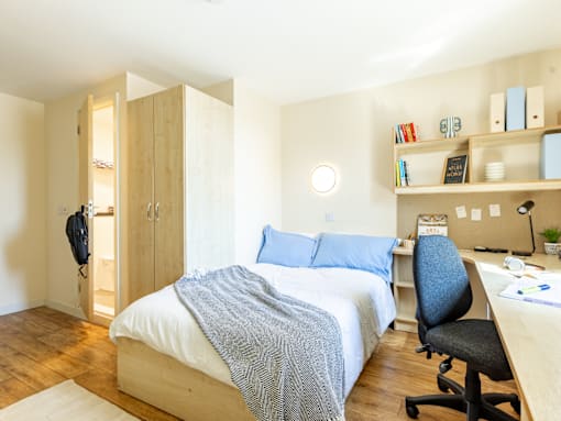 A bedroom with a bed, desk, and chair.
