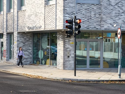 A woman is walking past the Great Court building.