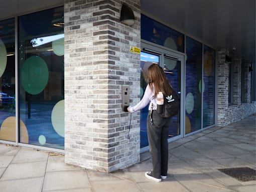 A woman is entering a building through a glass door.