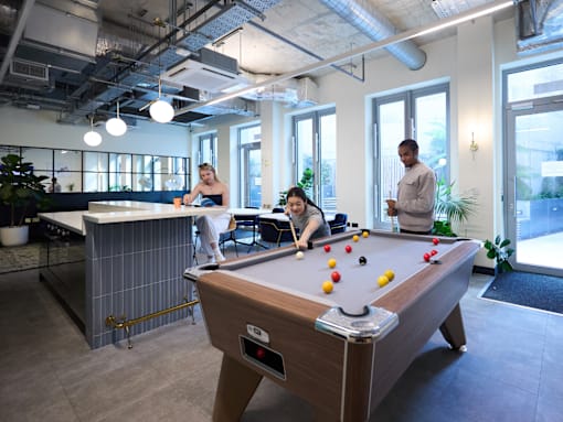 Three people playing pool in a room with a pool table.