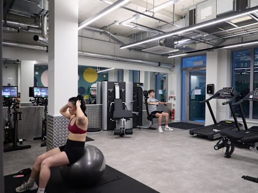 A woman is sitting on an exercise ball in a gym.