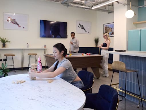 A woman is playing a game on a table in a room with other people.