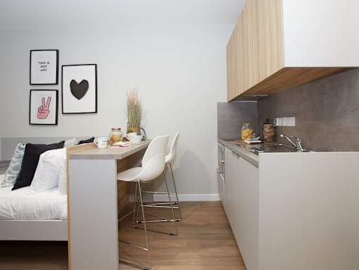 A kitchen with a white chair and a table with a vase of flowers on it.