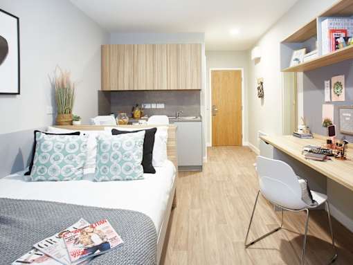 A bedroom with a bed, a desk, and a chair.
