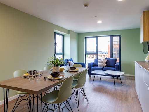 A dining room with a table set for two and a couch in the background.