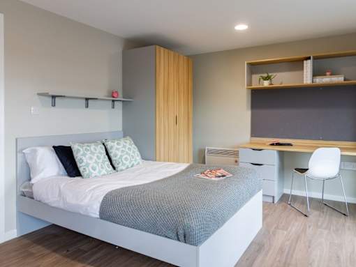 A bedroom with a bed, desk, and chair.