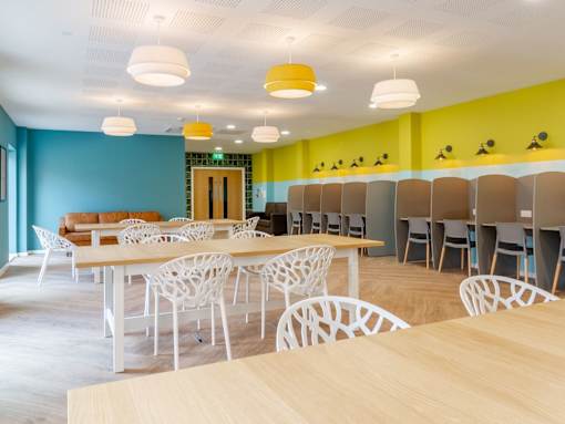 A room with tables and chairs and a blue wall.