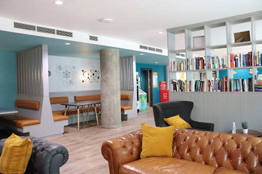 A room with a brown leather couch and a bookshelf filled with books.