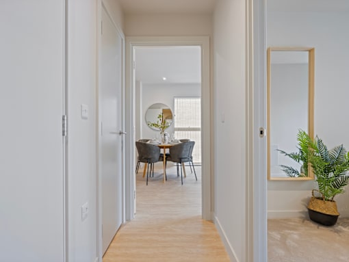 A dining room with a table set for two and a potted plant on the floor.