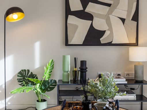 A table with a green plant and a vase with white flowers.