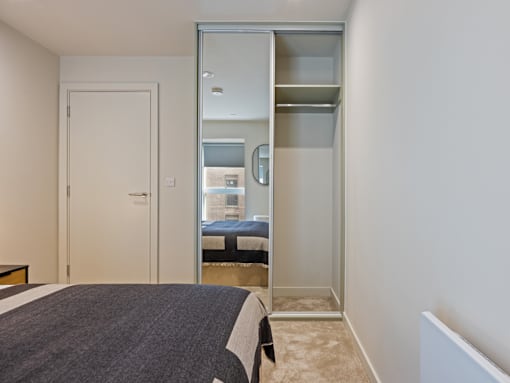 A bedroom with a bed, a mirror, and a closet.