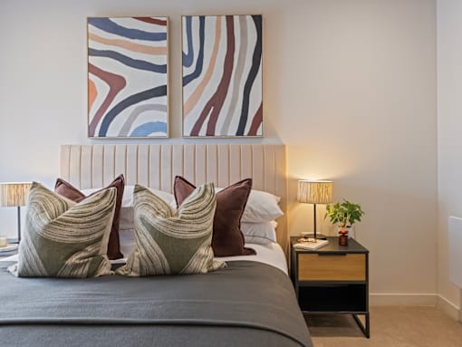 A bed with a grey sheet and four pillows with a brown and beige design.