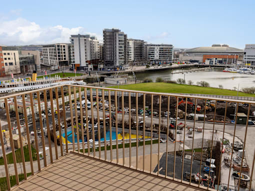 A view from a balcony overlooking a parking lot and buildings.