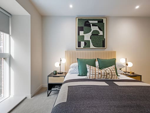 A bedroom with a bed, nightstands, and a painting on the wall.