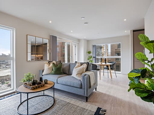 A living room with a grey couch, a coffee table, and a large window overlooking a cityscape.