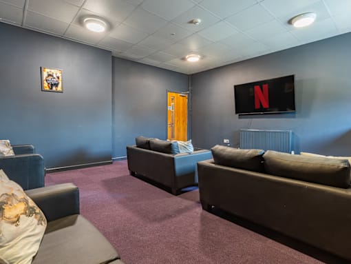 A living room with a couch, chair, and a television displaying the Netflix logo.