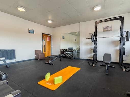 A gym with a weightlifting bar and weights.