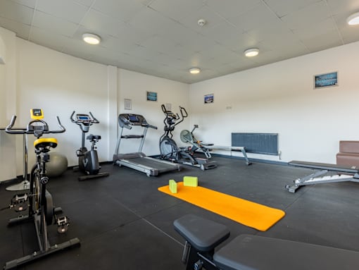 A gym with a variety of equipment including treadmills, stationary bikes, and weight machines.