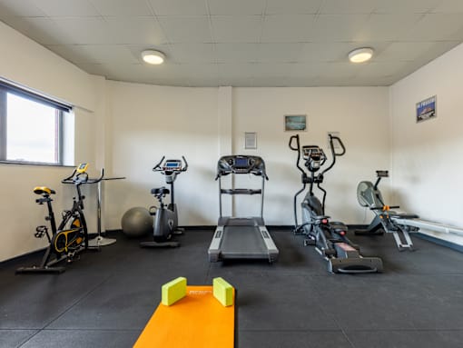 A gym room with a variety of exercise equipment.