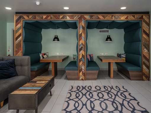 A room with a grey couch, a wooden table, and a patterned rug.
