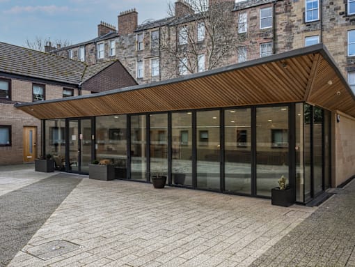 A modern extension to a traditional building with a wooden roof and glass walls.