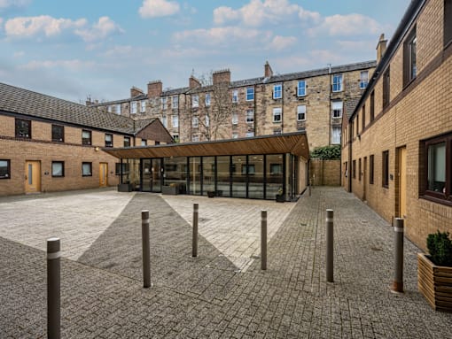 A courtyard with a brick floor and a building in the background.