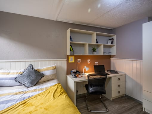 A bedroom with a bed, desk, and chair.