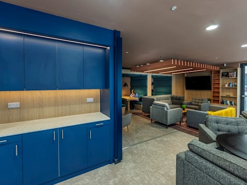 A room with blue cabinets and a grey sofa.